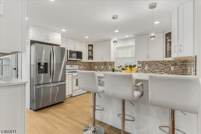1592 Front St, Scotch Plains Twp, NJ 07076 - kitchen with stainless steel appliances, a breakfast bar, white cabinetry, glass insert cabinets, and backsplash