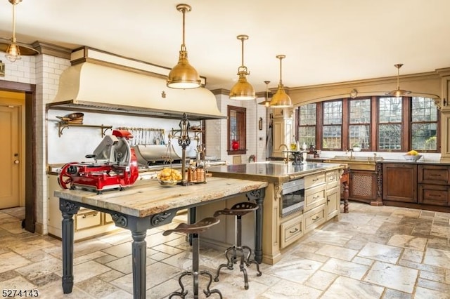 12 Canfield Rd, Morris Twp, NJ 07960 - kitchen with stone tile floors, hanging light fixtures, crown molding, and a center island with sink