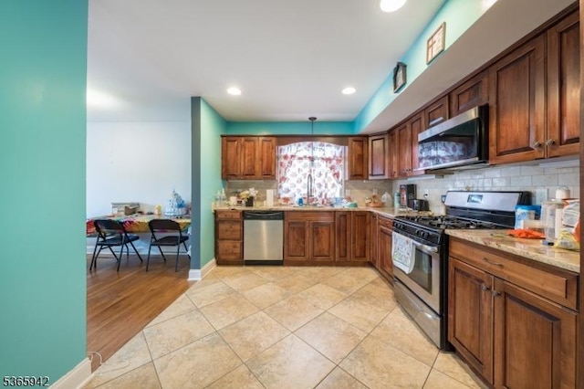 29 E Price St Unit 4, Linden City, NJ 07036 - kitchen featuring stainless steel appliances, decorative backsplash, light tile patterned floors, light stone countertops, and brown cabinets