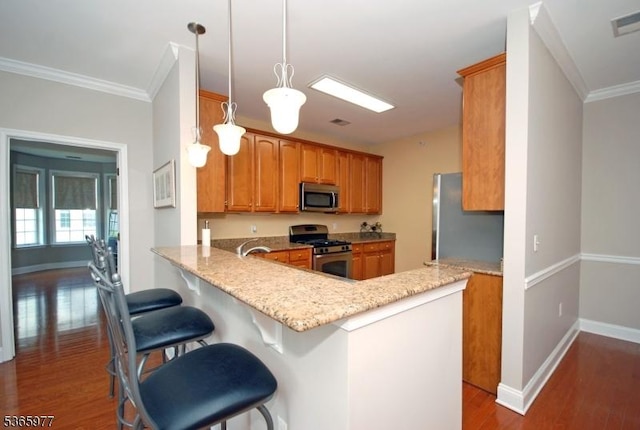 10 Cliff Rd Unit A3, Woodland Park, NJ 07424 - kitchen featuring appliances with stainless steel finishes, crown molding, dark wood-type flooring, brown cabinetry, and a peninsula