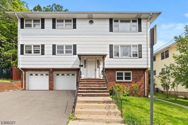 132 N 17th St, Prospect Park Boro, NJ 07508 - view of front of home with brick siding, an attached garage, asphalt driveway, and a front lawn
