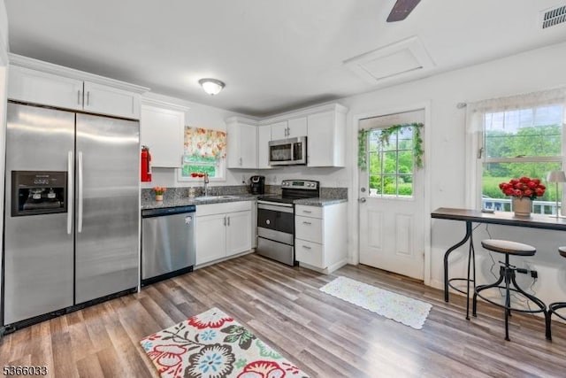 285 Stickles Pond Rd, Andover Twp, NJ 07860 - kitchen featuring appliances with stainless steel finishes, white cabinets, light wood-type flooring, and dark stone countertops