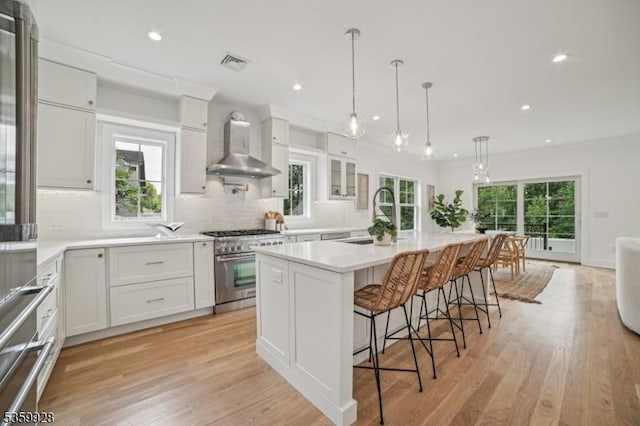 151 Center Ave, Chatham Boro, NJ 07928 - kitchen with wall chimney exhaust hood, high end range, tasteful backsplash, a breakfast bar, and a center island with sink