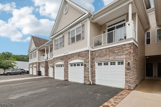 28 Elston Ct Unit 28, Wanaque Boro, NJ 07420 - view of home's exterior featuring stone siding, a balcony, an attached garage, and driveway