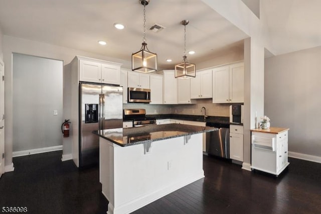 28 Elston Ct Unit 28, Wanaque Boro, NJ 07420 - kitchen with appliances with stainless steel finishes, white cabinetry, a breakfast bar area, backsplash, and a center island