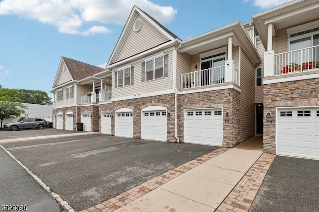 28 Elston Ct Unit 28, Wanaque Boro, NJ 07420 - view of front of house with stone siding, driveway, a garage, and a balcony