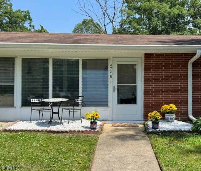 472B Thornbury Ct, Lakewood Twp, NJ 08701 - view of exterior entry featuring brick siding, a shingled roof, and a lawn