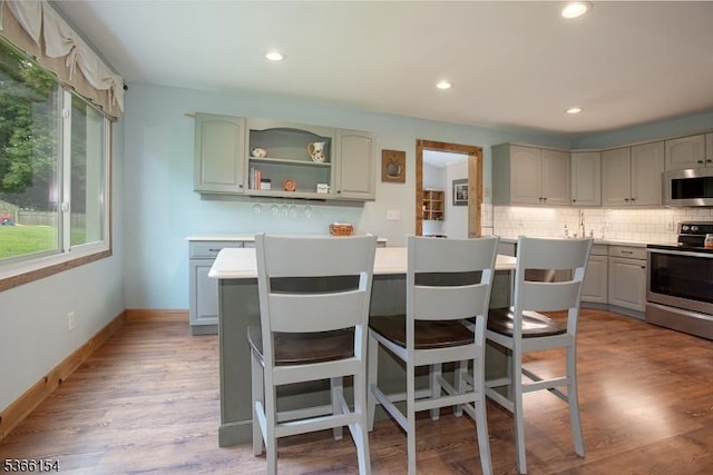 105 Rolling Acres Dr, Hampton Twp, NJ 07860 - kitchen featuring appliances with stainless steel finishes, a kitchen island, decorative backsplash, a breakfast bar, and wood finished floors