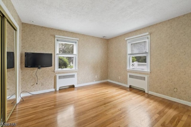 3 Casey Ave, East Hanover Twp, NJ 07936 - unfurnished living room featuring radiator, wood finished floors, a textured ceiling, and wallpapered walls