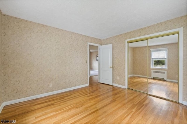 3 Casey Ave, East Hanover Twp, NJ 07936 - unfurnished bedroom with radiator heating unit, wood finished floors, wallpapered walls, and a closet