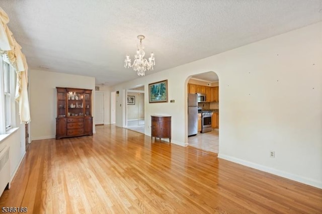 3 Casey Ave, East Hanover Twp, NJ 07936 - unfurnished living room with arched walkways, light wood-style flooring, a chandelier, radiator heating unit, and a textured ceiling