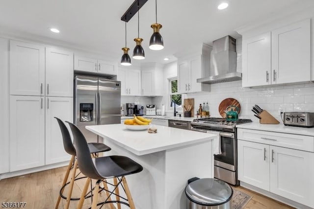 24 Roxbury Dr, Roxbury Twp, NJ 07847 - kitchen with stainless steel appliances, wall chimney exhaust hood, a kitchen bar, white cabinetry, and a kitchen island