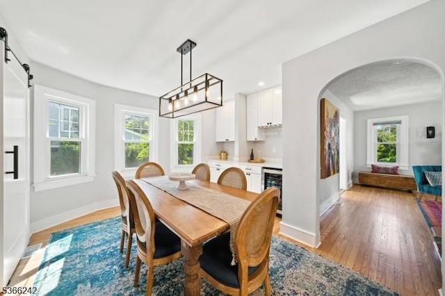 86 Riverside Dr, Denville Twp, NJ 07834 - dining area featuring beverage cooler, light wood-style flooring, arched walkways, and bar area
