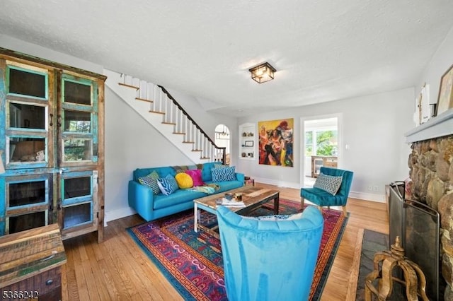 86 Riverside Dr, Denville Twp, NJ 07834 - living area with stairway, wood finished floors, a textured ceiling, and a stone fireplace