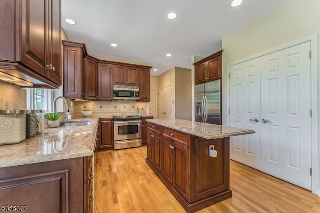 4 Coryell Ct, Raritan Twp, NJ 08822 - kitchen featuring appliances with stainless steel finishes, light wood-style flooring, decorative backsplash, a center island, and light stone counters