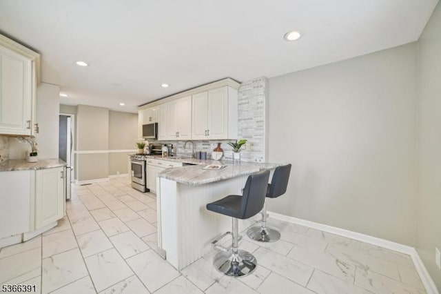 980 Moessner Ave, Union Twp, NJ 07083 - kitchen with stainless steel appliances, light marble finish flooring, a peninsula, a kitchen bar, and recessed lighting