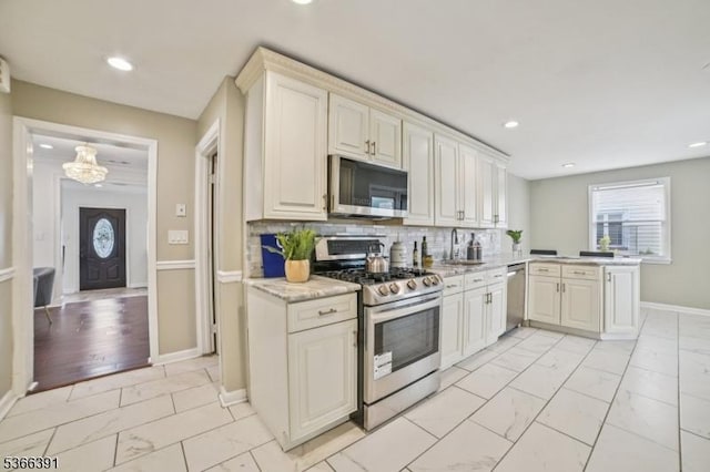 980 Moessner Ave, Union Twp, NJ 07083 - kitchen featuring appliances with stainless steel finishes, light marble finish floors, a peninsula, recessed lighting, and decorative backsplash