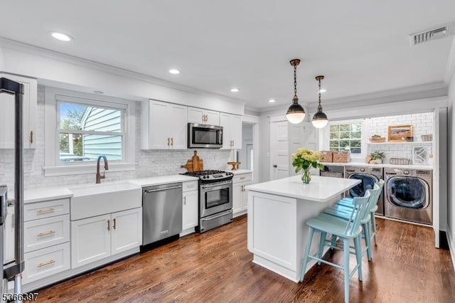 913 Columbus Ave, Westfield Town, NJ 07090 - kitchen with stainless steel appliances, washer and clothes dryer, ornamental molding, decorative backsplash, and light countertops