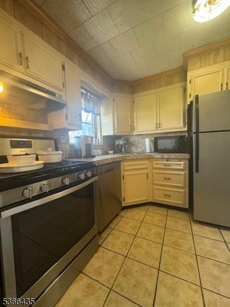 1221 Union St, Linden City, NJ 07036 - kitchen with appliances with stainless steel finishes, backsplash, light tile patterned floors, white cabinetry, and light countertops