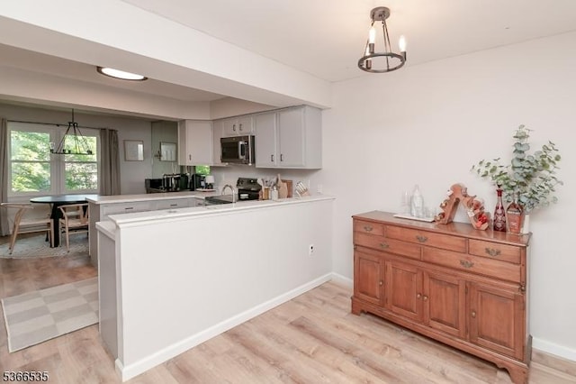 11 Killdeer Dr, Allamuchy Twp, NJ 07840 - kitchen featuring stainless steel microwave, a peninsula, light wood-type flooring, a chandelier, and decorative light fixtures