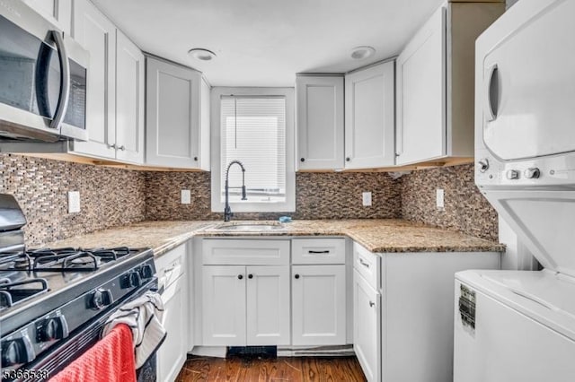 853 Westfield Ave, Rahway City, NJ 07065 - kitchen with appliances with stainless steel finishes, stacked washer / dryer, dark wood finished floors, light stone counters, and white cabinetry