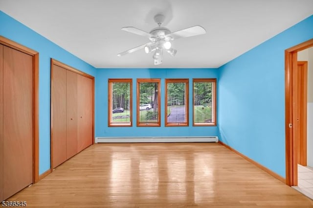 86 Underrock Rd, Sparta Twp, NJ 07871 - unfurnished bedroom featuring a baseboard heating unit, two closets, multiple windows, and light wood-type flooring