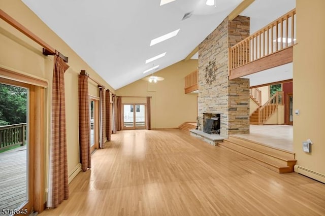 86 Underrock Rd, Sparta Twp, NJ 07871 - unfurnished living room with high vaulted ceiling, light wood-style flooring, a skylight, stairway, and a stone fireplace