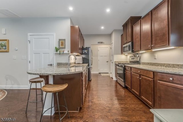 7 Harrier Ln, Washington Twp, NJ 07882 - kitchen featuring appliances with stainless steel finishes, a kitchen breakfast bar, light stone counters, dark wood finished floors, and a peninsula