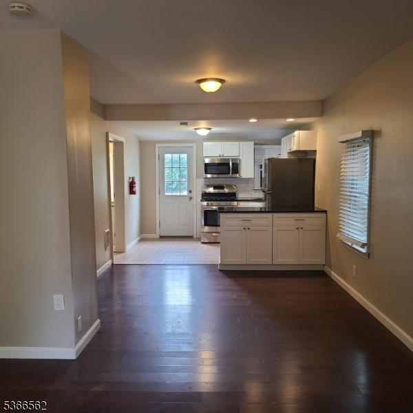16 Ransome Pl, Plainfield City, NJ 07063 - kitchen featuring appliances with stainless steel finishes, dark wood-style floors, dark countertops, and white cabinetry