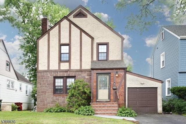 393 High St, Nutley Twp, NJ 07110 - tudor-style house with entry steps, stone siding, a chimney, an attached garage, and driveway