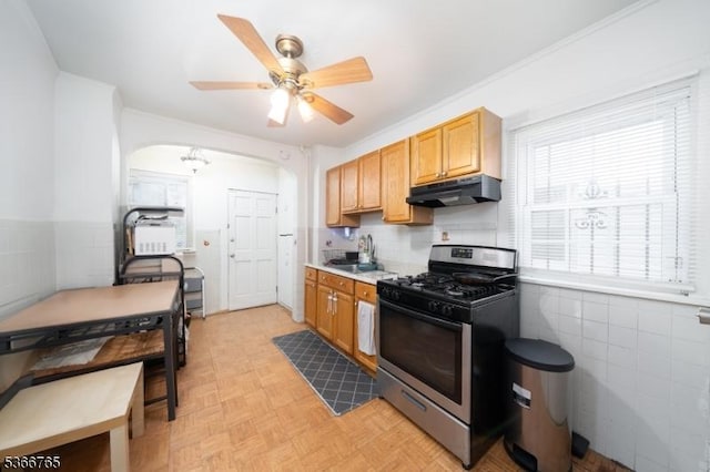 129 Ball St, Irvington Twp, NJ 07111 - kitchen with stainless steel gas stove, under cabinet range hood, arched walkways, a ceiling fan, and light countertops