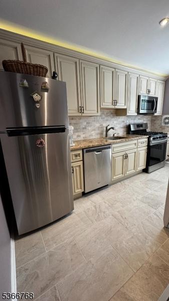 53 Sandra Cir Unit 4, Westfield Town, NJ 07090 - kitchen with stainless steel appliances, decorative backsplash, cream cabinets, and light stone counters