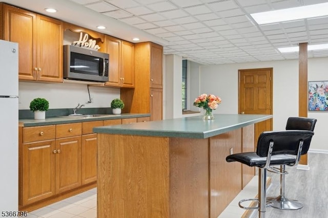 17 N Ridge Rd, Denville Twp, NJ 07834 - kitchen with stainless steel microwave, freestanding refrigerator, a kitchen breakfast bar, a kitchen island, and brown cabinetry