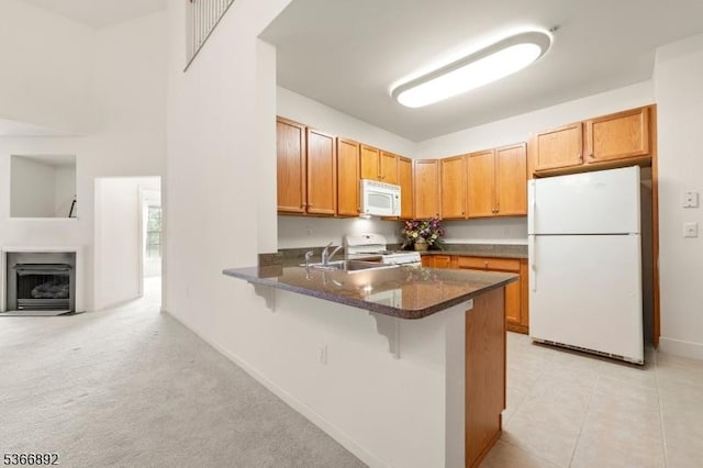 7303 Ravenscroft Rd Unit 7303, Clifton City, NJ 07013 - kitchen featuring white appliances, a peninsula, a kitchen breakfast bar, a fireplace with flush hearth, and dark stone counters