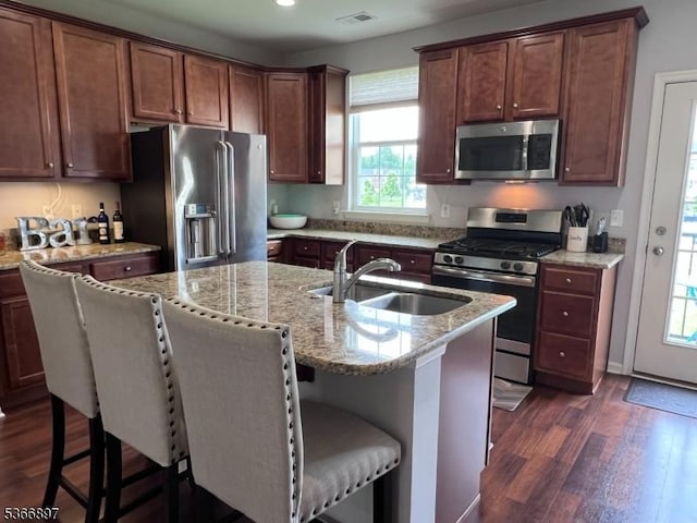 108 Creekside Way, Burlington Twp, NJ 08016 - kitchen featuring stainless steel appliances, dark wood-style floors, light stone countertops, a breakfast bar area, and an island with sink