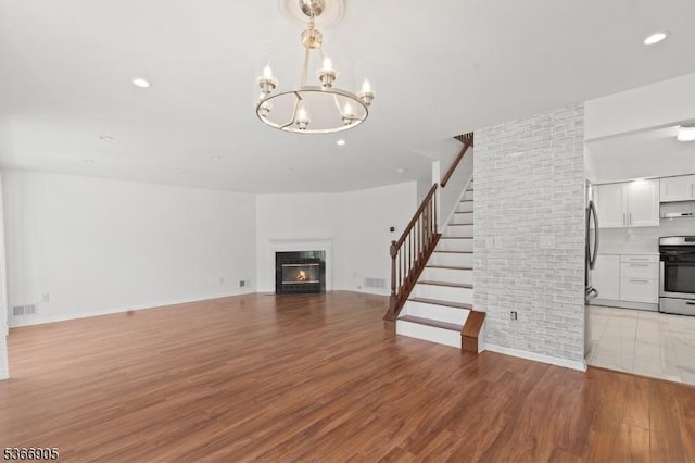 4106 Dilts Ln, Bridgewater Twp, NJ 08807 - unfurnished living room featuring a chandelier, wood finished floors, a warm lit fireplace, stairway, and recessed lighting