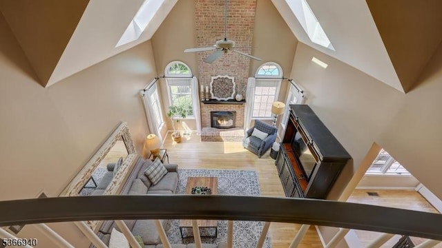 24 Montfort Dr, Montgomery Twp, NJ 08502 - living area with a skylight, high vaulted ceiling, wood finished floors, ceiling fan, and a brick fireplace