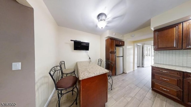 979 Lorraine Ave, Union Twp, NJ 07083 - kitchen featuring freestanding refrigerator, a kitchen breakfast bar, backsplash, light stone countertops, and a peninsula