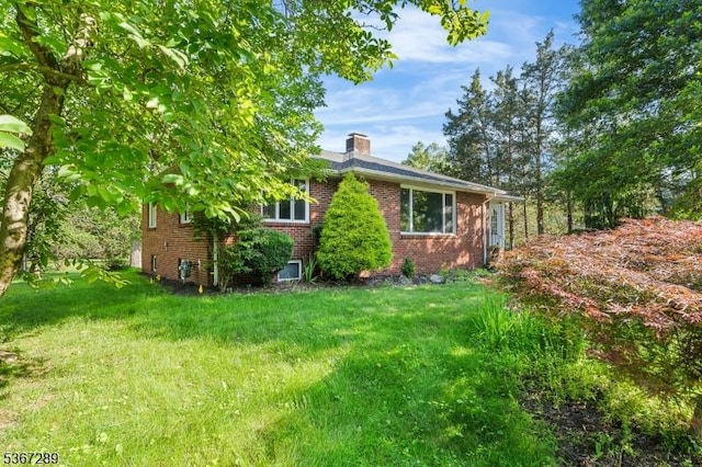 77 John E Busch Ave, Franklin Twp, NJ 08873 - view of side of property featuring a chimney, brick siding, and a yard