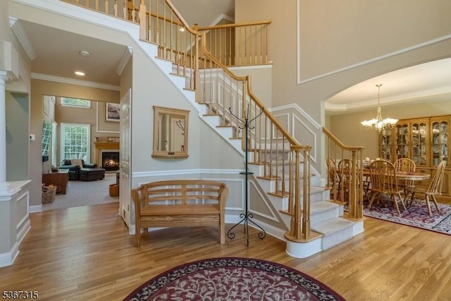 3 Mackenzie Ct, Sparta Twp, NJ 07871 - stairway featuring a high ceiling, wood finished floors, ornamental molding, arched walkways, and a lit fireplace