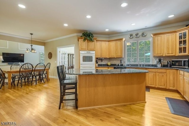 3 Mackenzie Ct, Sparta Twp, NJ 07871 - kitchen with light wood-style floors, a center island, a kitchen breakfast bar, glass insert cabinets, and tasteful backsplash