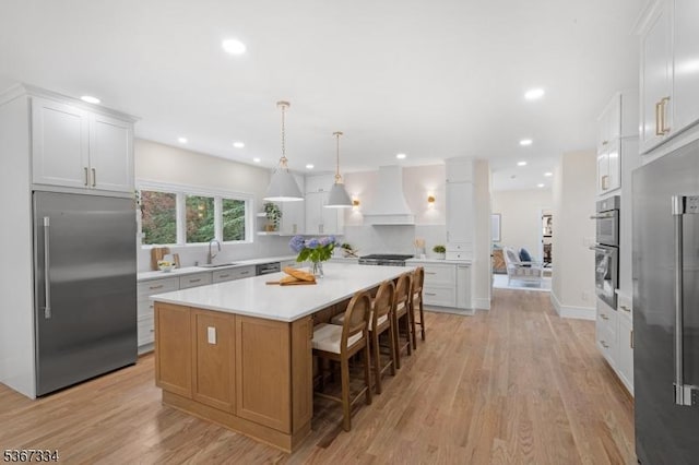 211 Spencer Rd, Bernards Twp, NJ 07920 - kitchen with stainless steel appliances, custom exhaust hood, light countertops, a center island, and light wood-style flooring
