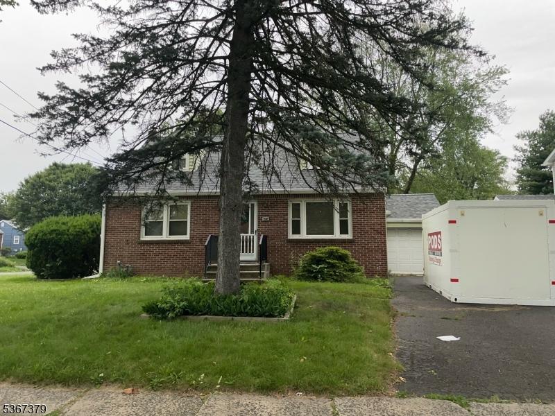 1598 Front St, Scotch Plains Twp, NJ 07076 - view of front of house with brick siding, an attached garage, driveway, and a front lawn