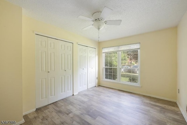 136 Woodward Ln, Bernards Twp, NJ 07920 - unfurnished bedroom with multiple closets, wood finished floors, a textured ceiling, and a ceiling fan