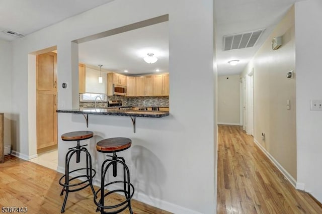 830 Pennsylvania Ave, Lyndhurst Twp, NJ 07071 - kitchen featuring a breakfast bar area, stainless steel microwave, light wood-style floors, and backsplash