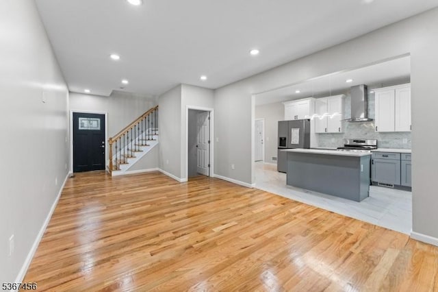 331 W Ln, Clark Twp, NJ 07066 - kitchen featuring stainless steel appliances, wall chimney range hood, light wood finished floors, a kitchen island, and white cabinets