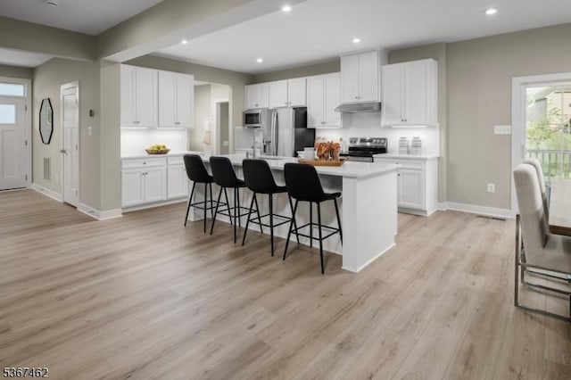 7 Glacier Way, Union Twp, NJ 08867 - kitchen with stainless steel appliances, under cabinet range hood, light countertops, light wood-style flooring, and a kitchen breakfast bar