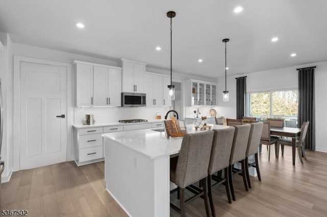 14 Glacier Way, Union Twp, NJ 08867 - kitchen featuring stainless steel microwave, a center island with sink, light wood finished floors, a kitchen bar, and white cabinets