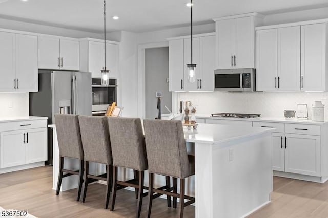 14 Glacier Way, Union Twp, NJ 08867 - kitchen with appliances with stainless steel finishes, light wood-style floors, backsplash, white cabinets, and a kitchen island with sink