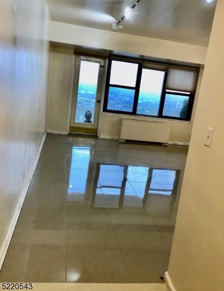 285 Aycrigg Ave Unit 22D, Passaic City, NJ 07055 - tiled spare room featuring radiator heating unit and baseboards